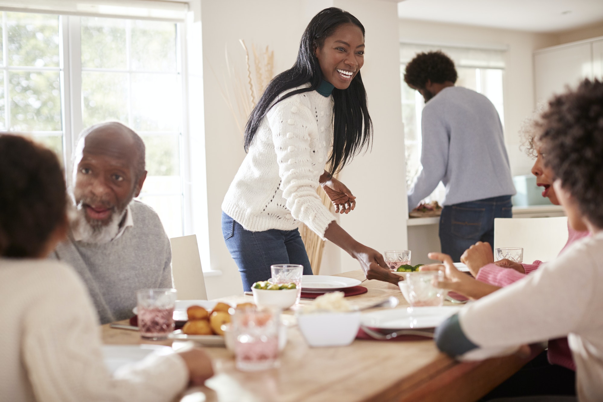 Black couple bringing food to the table for Sunday family dinner for the kids and grandparents